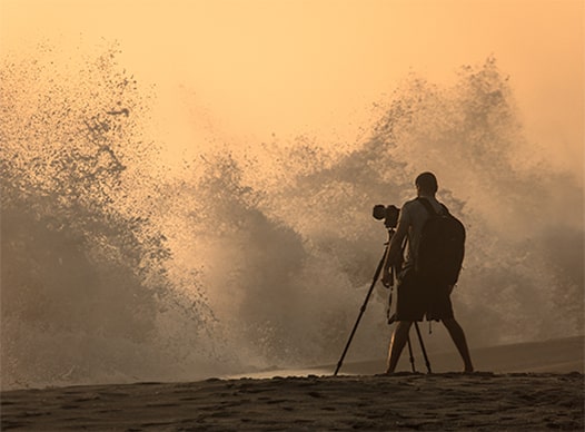 man taking a photo of waves crashing at blowing rock