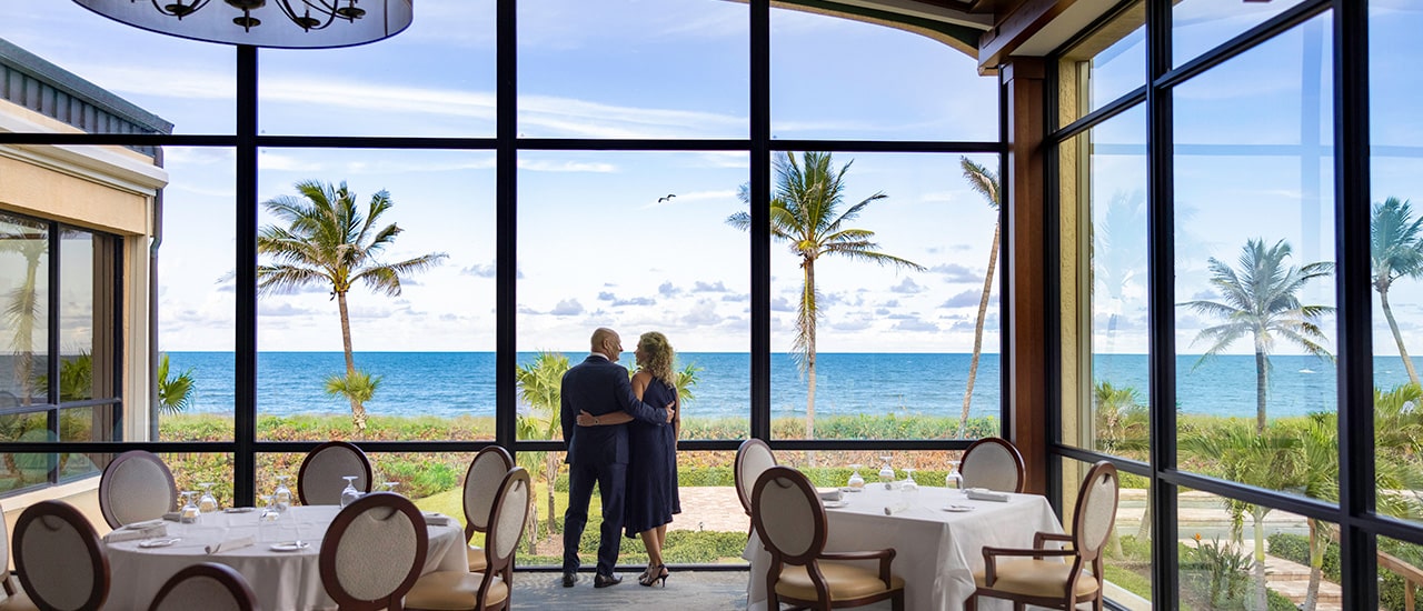 couple looking out of windows at sailfish point dining room