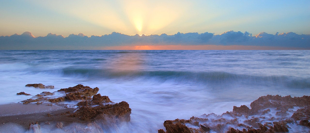 sunrise over rocks in ocean