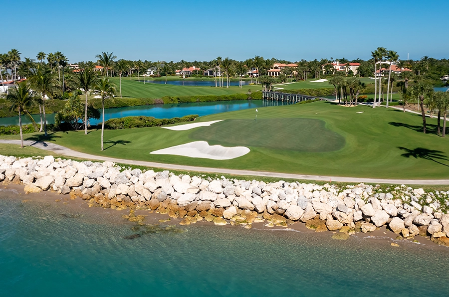 Waterfront golf hole at Sailfish Point with bright greens and turquoise shoreline.