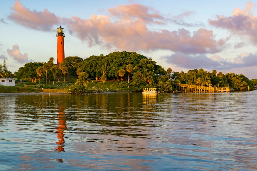 Lighthouse on a shoreline with trees, docks, and calm water