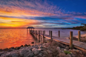 Wooden pier extending into water at sunset