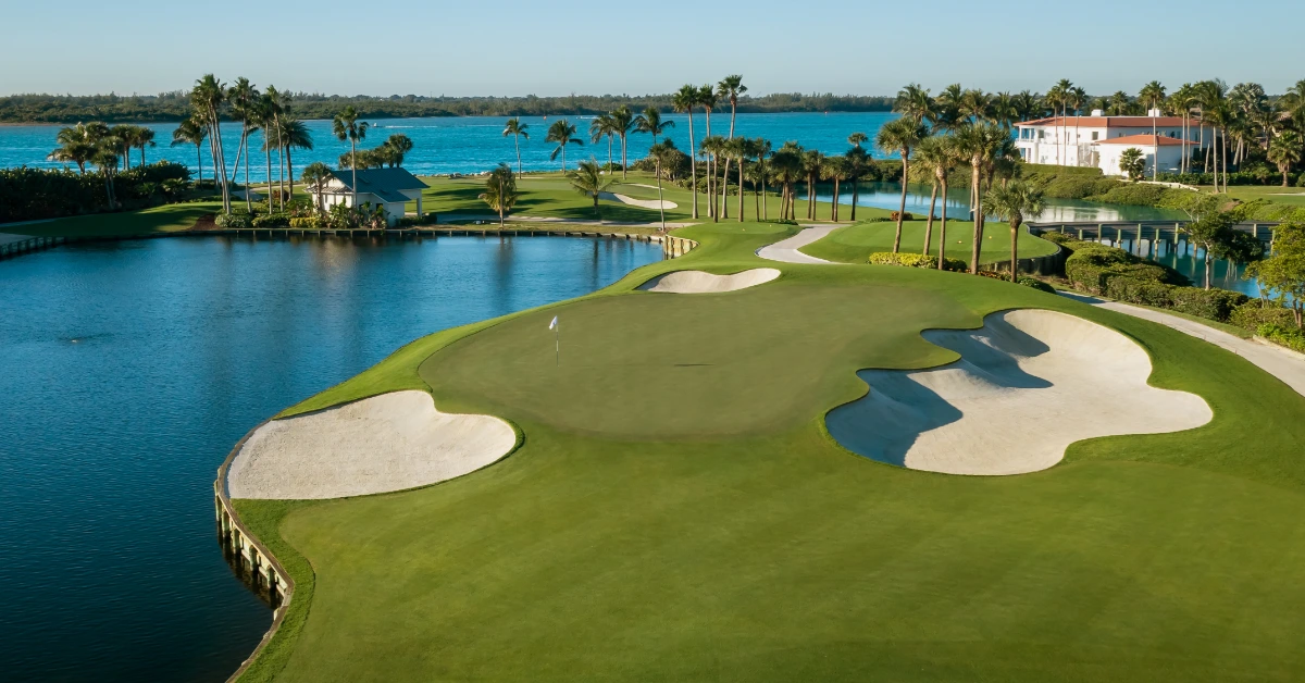 Golf green with sand bunkers surrounded by water and palm trees