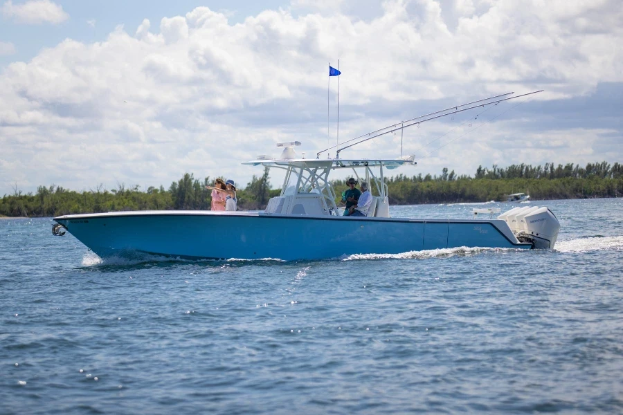 Center console boat with people cruising across open water under a bright sky.