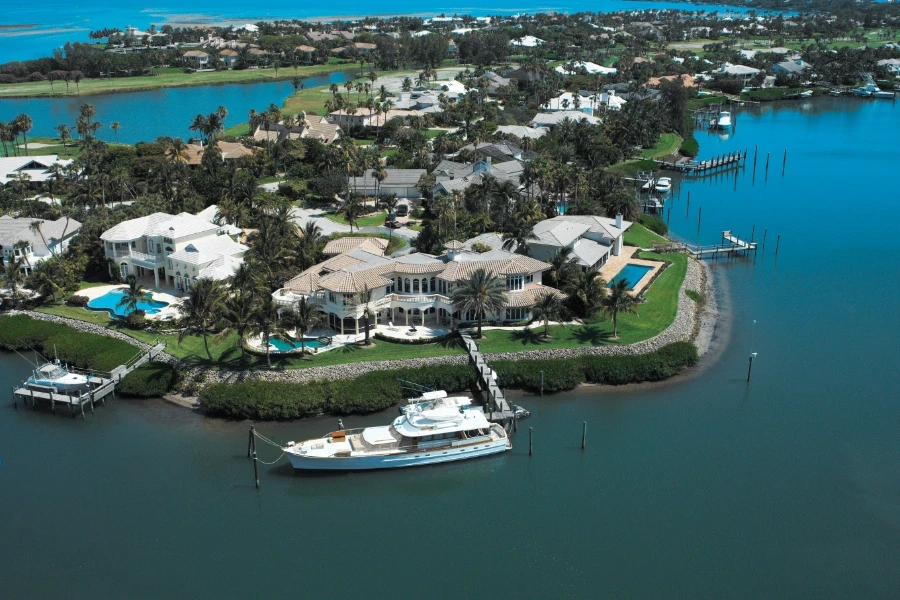 Waterfront mansion with private dock and yacht along a coastal canal.
