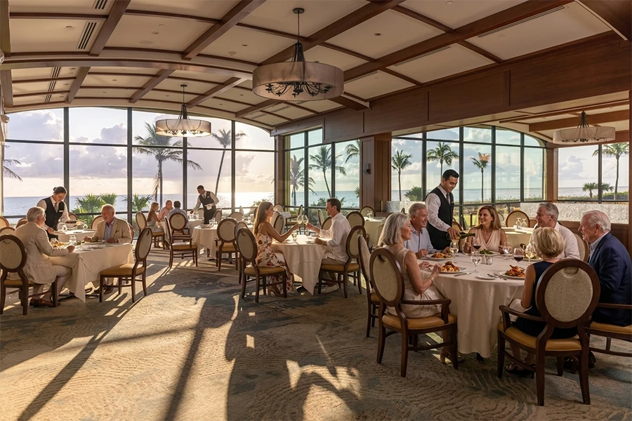 Guests dining in restaurant with ocean view through large windows.